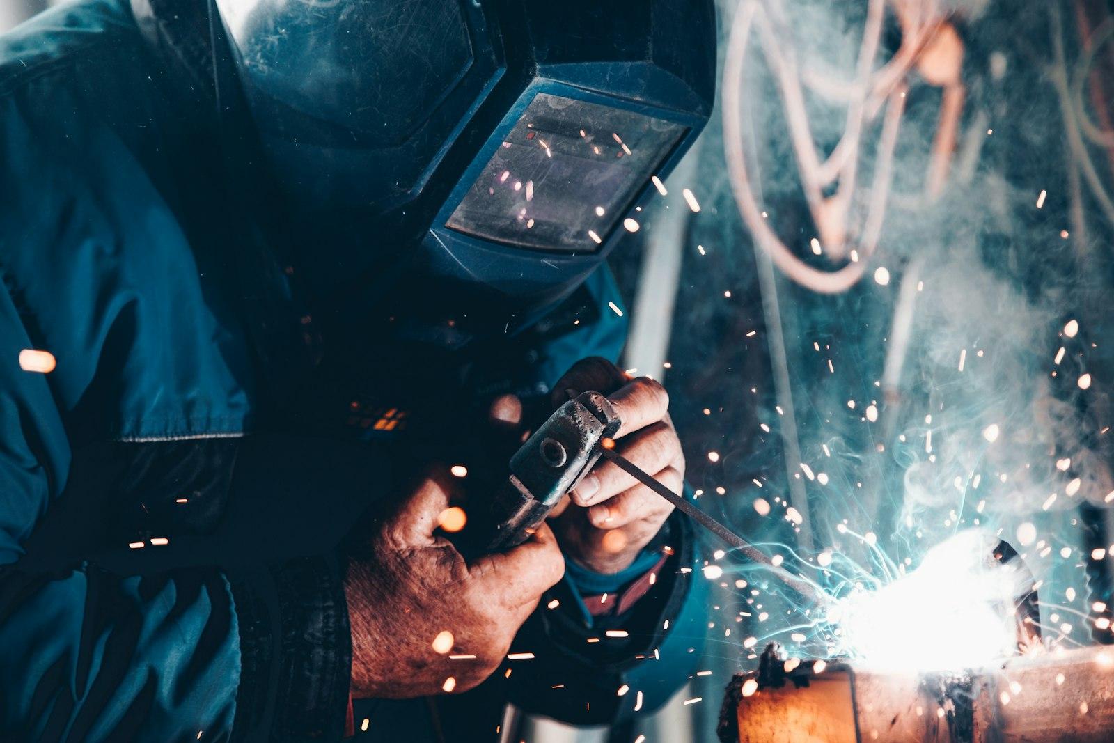 Certified welder fabricating a steel joint with sparks flying